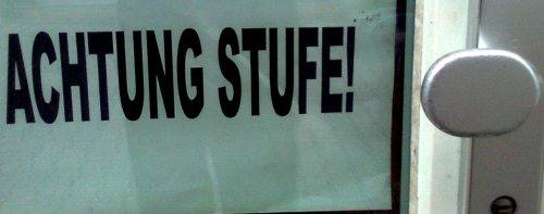 A warning of more stuff ('Mind the step) sign at a Charity Shop